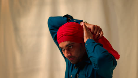 Close-Up-Studio-Shot-Of-Senior-Sikh-Man-With-Beard-Tying-Fabric-For-Turban-Against-Plain-Background-Shot-In-Real-Time-3